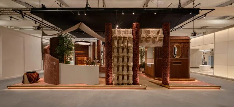 Front view of the Kohler booth with black track and spotlights above carved columns and raised display platforms