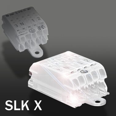 An SLK 5 luminaire connector behind a smaller lit SLK X connector on a dark background