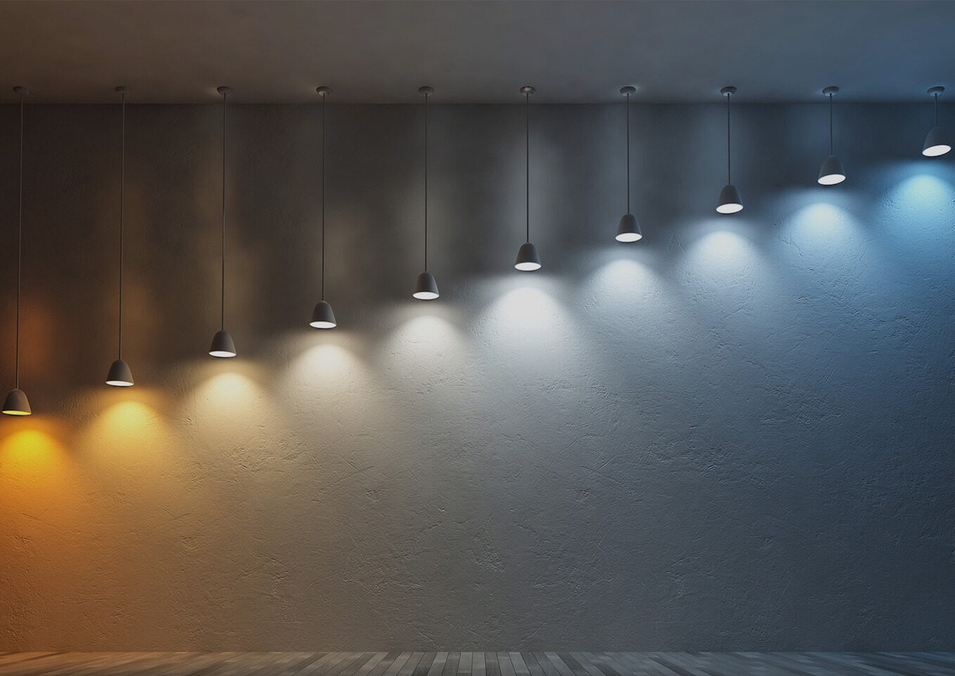 Row of pendant lights against a dark wall, shifting from warm amber on the left to cool white on the right