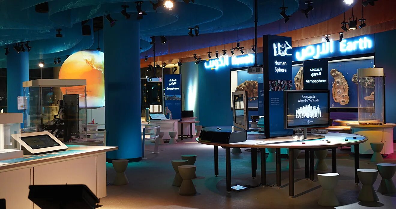 Earth gallery at TSCK with blue columns, display cases, an interactive table and track spotlights overhead