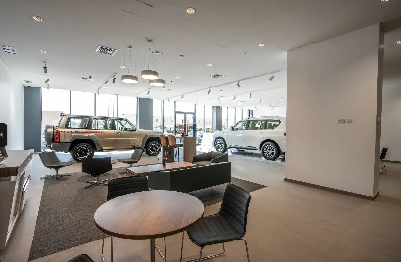 Nissan showroom lounge with pendant lights over seating, track spotlights on the ceiling and vehicles by the glazed frontage