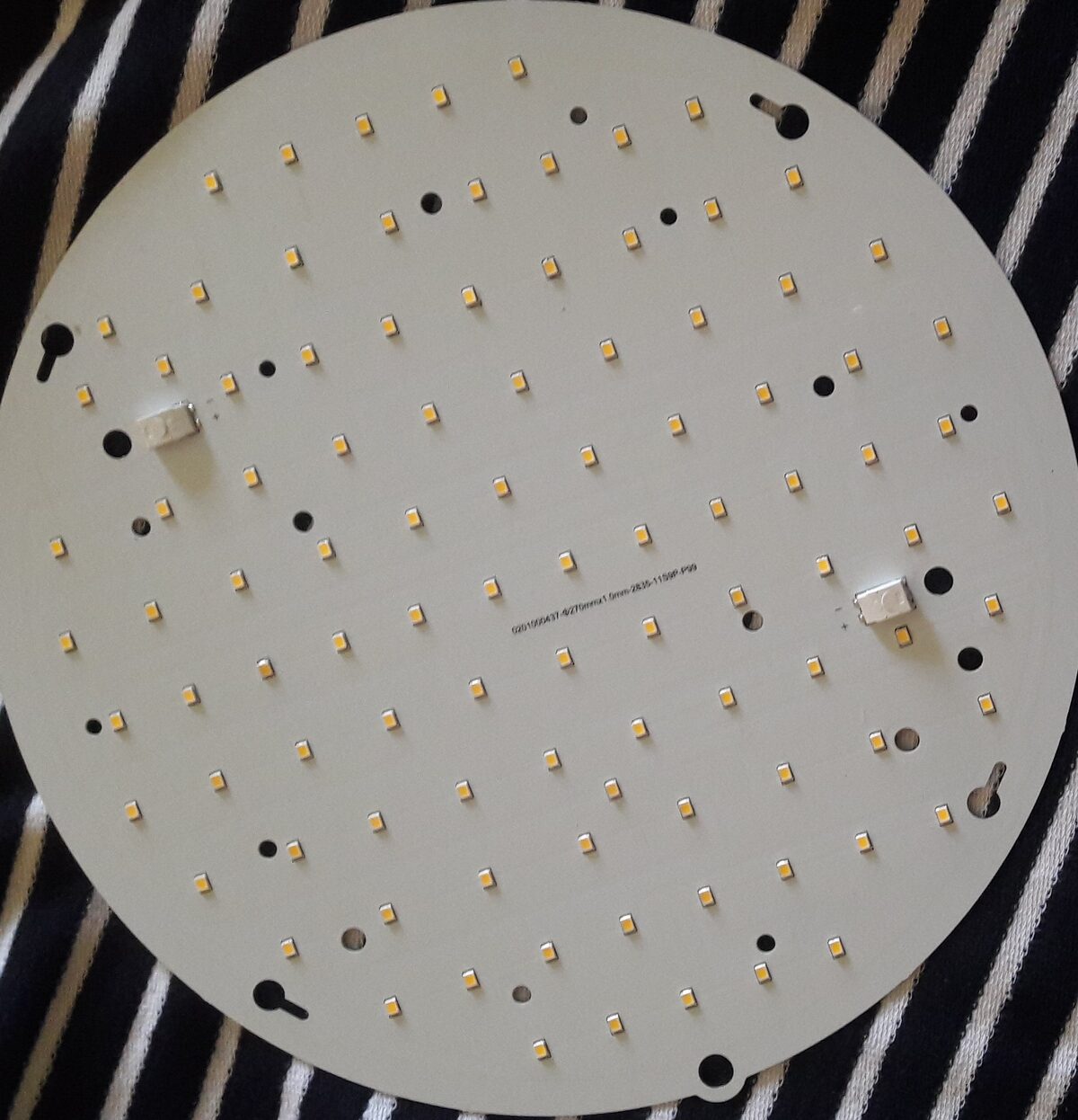 Round white aluminium LED board, 270 mm across, with an evenly spaced grid of small yellow 2835 LEDs, two connectors and keyhole fixing slots around the edge