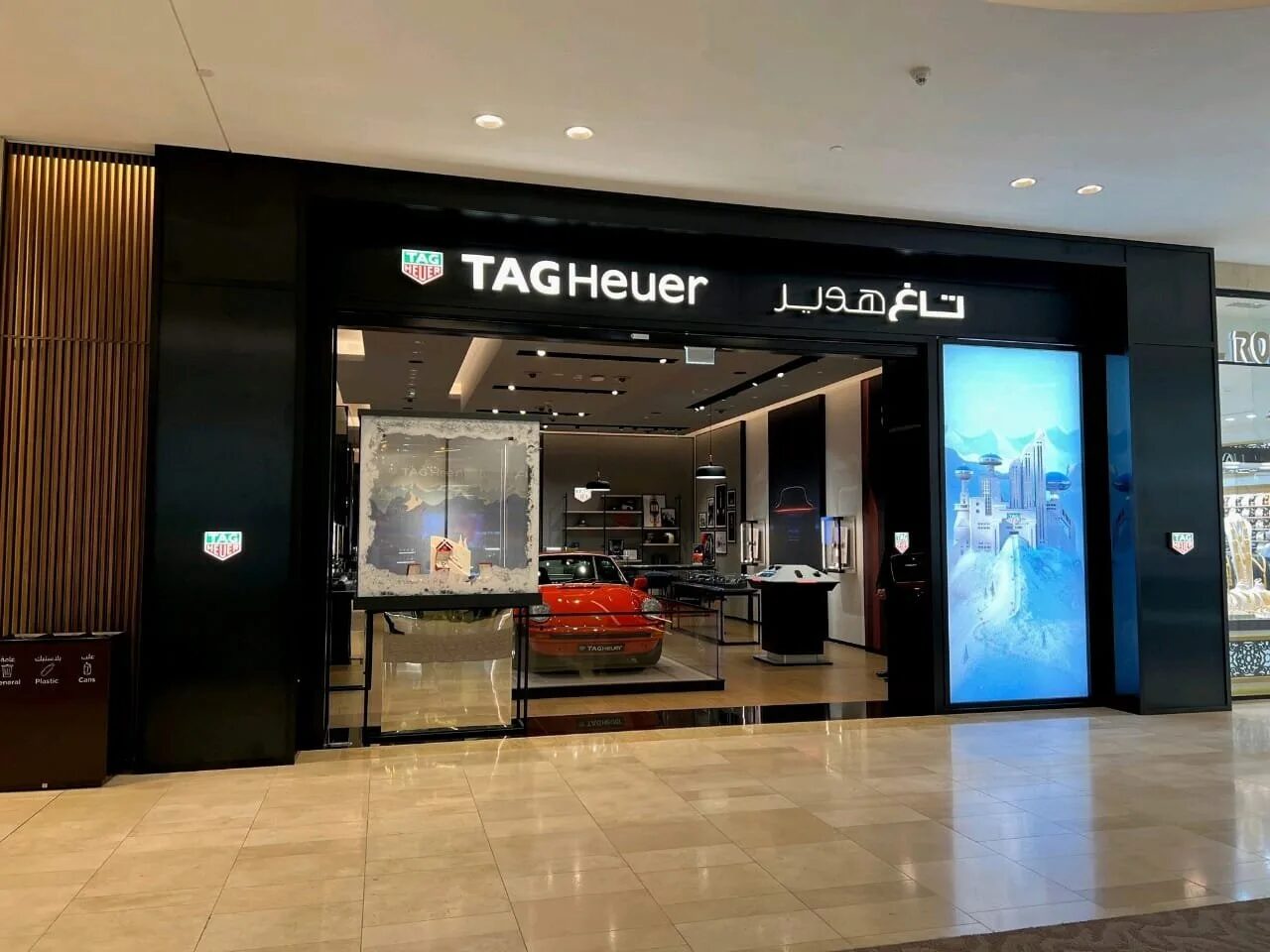 Tag Heuer shopfront at Yas Mall with a black frame, illuminated graphics and the red car display visible inside