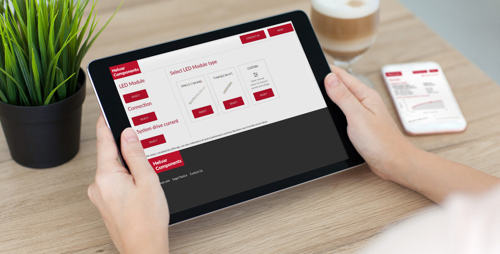 Helvar LEDesign tool open on a tablet held in two hands, with the mobile app on a phone in the background